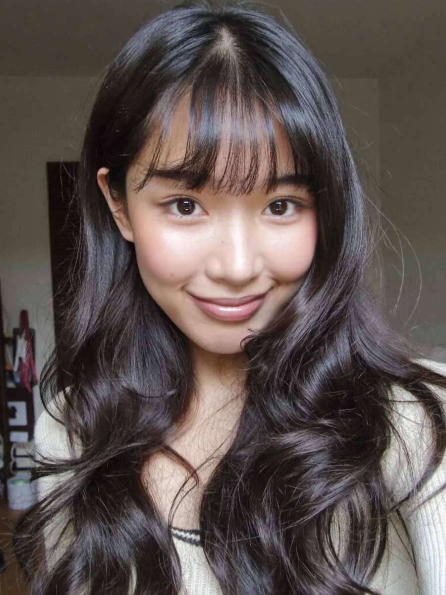 A casual selfie of a young woman with long black hair and bangs